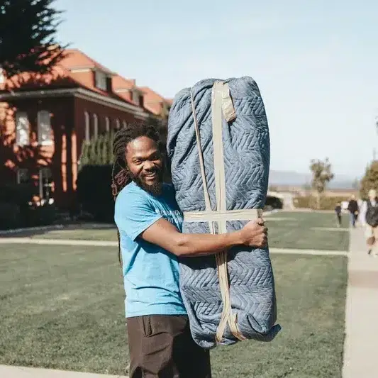 Poseidon Moving professional holding wrapped furniture with a smile