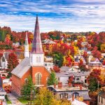 Scenic view of Vermont in fall with colorful foliage and historic church steeples in a small town.