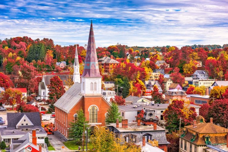 Scenic view of Vermont in fall with colorful foliage and historic church steeples in a small town.