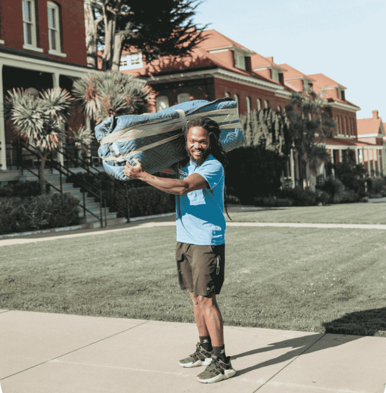 Smiling Poseidon Moving foreman carrying wrapped furniture