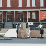 Poseidon Moving Company team offloading furniture and boxes from a branded moving truck at customer destination