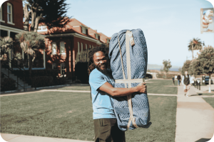Poseidon Moving Company crew member smiling at the camera while holding a wrapped furniture piece in a moving blanket