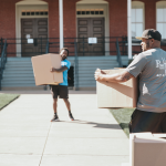 Poseidon Moving Company team carrying boxes during a move on a sunny day.