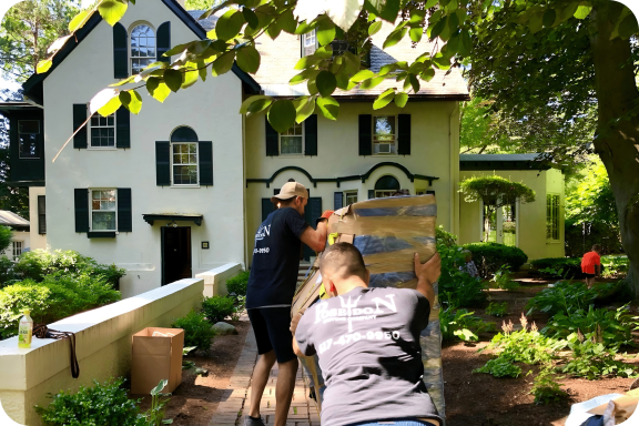 Poseidon Moving Crew Handling a Delivery Professional movers from Poseidon Moving transporting wrapped furniture through a garden walkway.