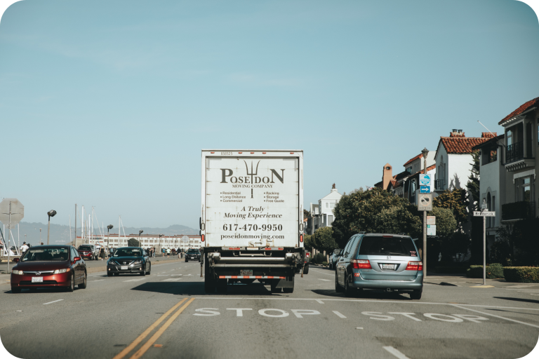 Poseidon Moving truck driving through a scenic residential area