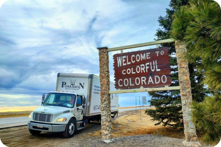 Poseidon Moving truck parked next to “Welcome to Colorful Colorado” highway sign