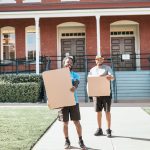 Two Poseidon movers carrying moving boxes during a residential move