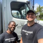 Two Poseidon Moving Company crew members smiling in front of a moving truck