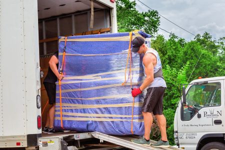 Poseidon movers loading a fully wrapped furniture item into a moving truck